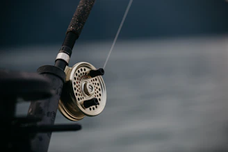Close-up of a sleek, handcrafted fishing rod with elegant detailing in a natural wood finish.