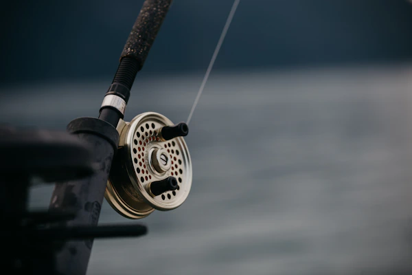 Close-up of a sleek, handcrafted fishing rod with elegant detailing in a natural wood finish.