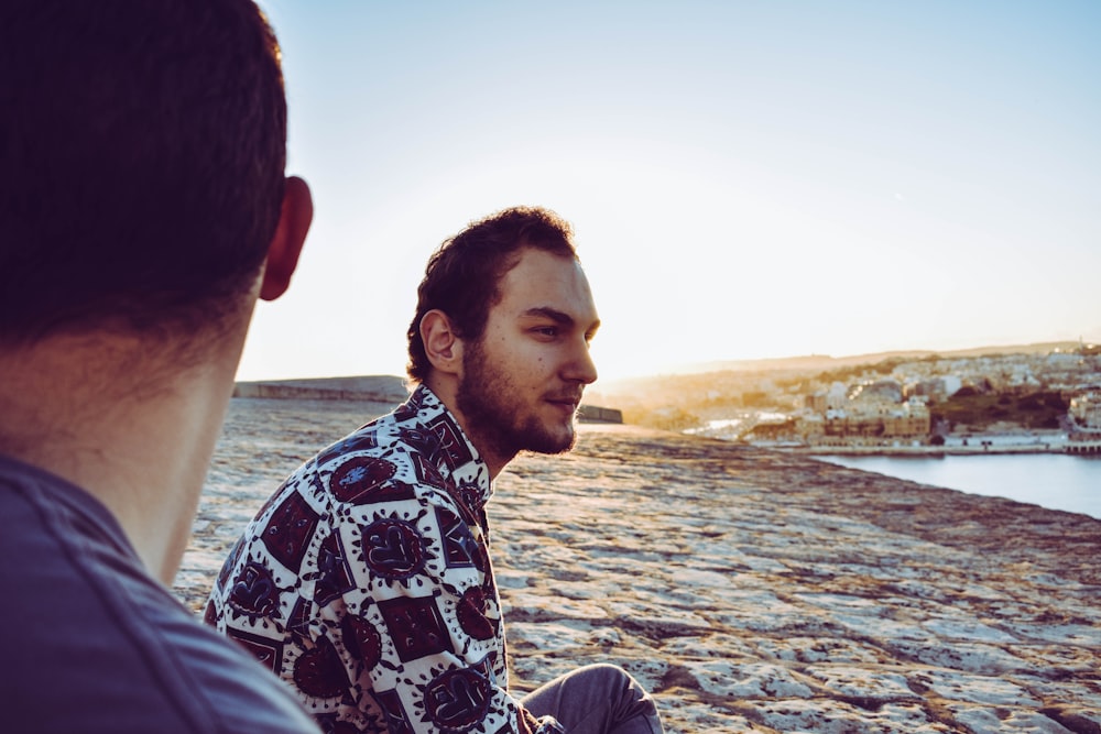 two men sits near shore