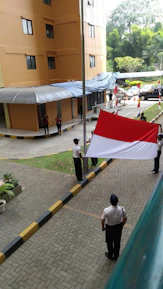 School children proudly holding red and white banners in a festive flag-raising ceremony.