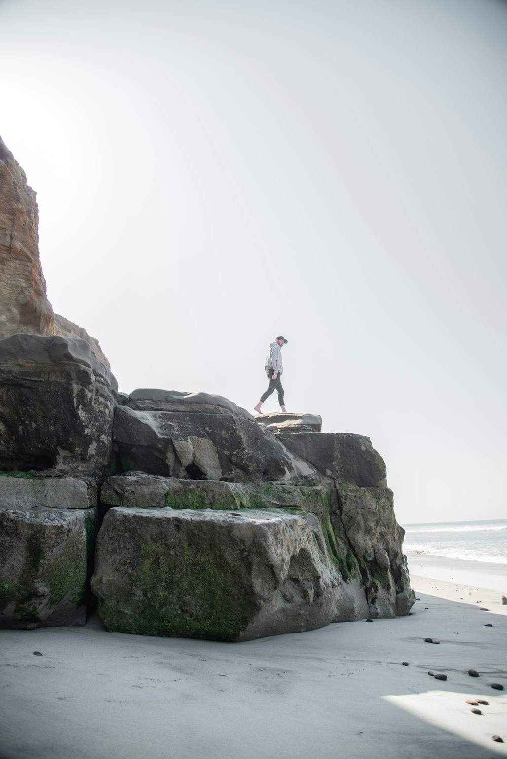 man at a gray cliff by a beach