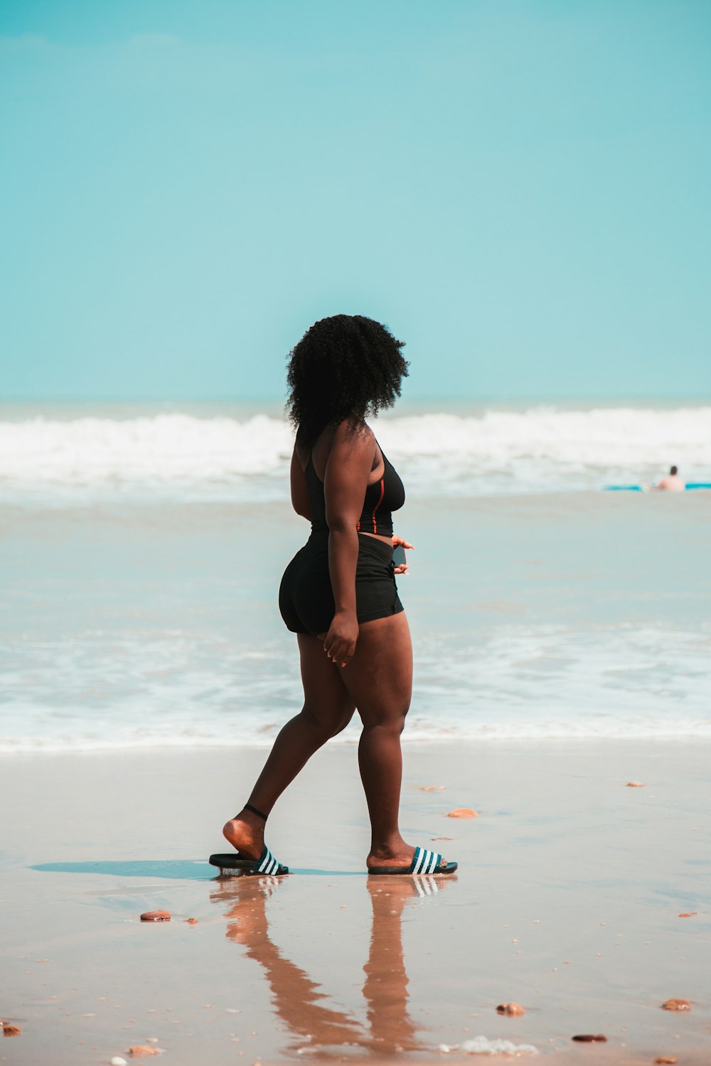 donna che cammina vicino alla riva del mare di fronte al suo lato destro