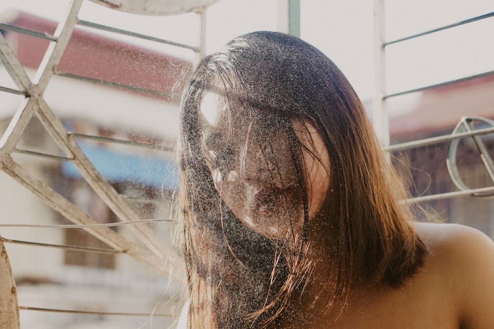 topless woman covering face with hair