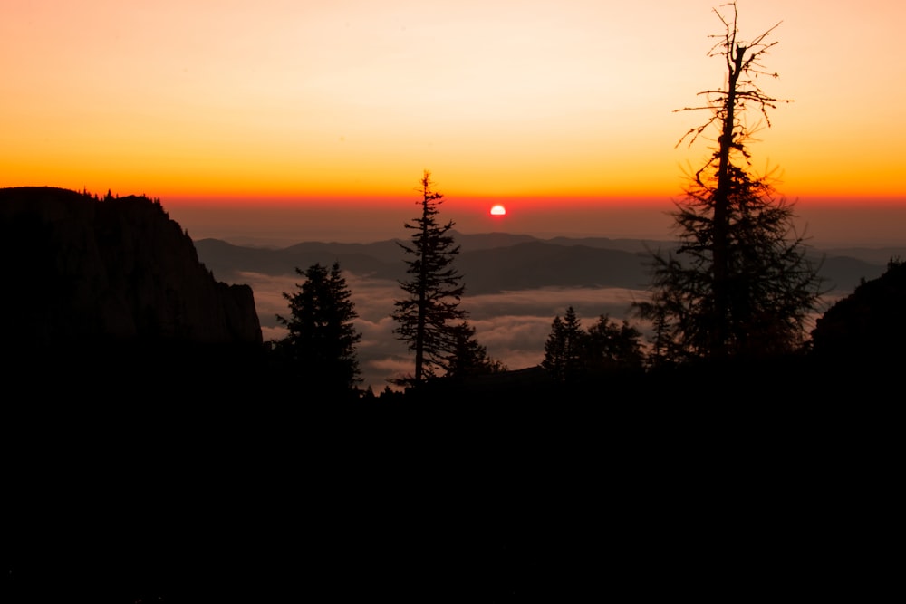 the sun is setting over the mountains and trees