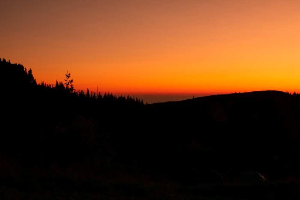 the sun is setting over the mountains and trees