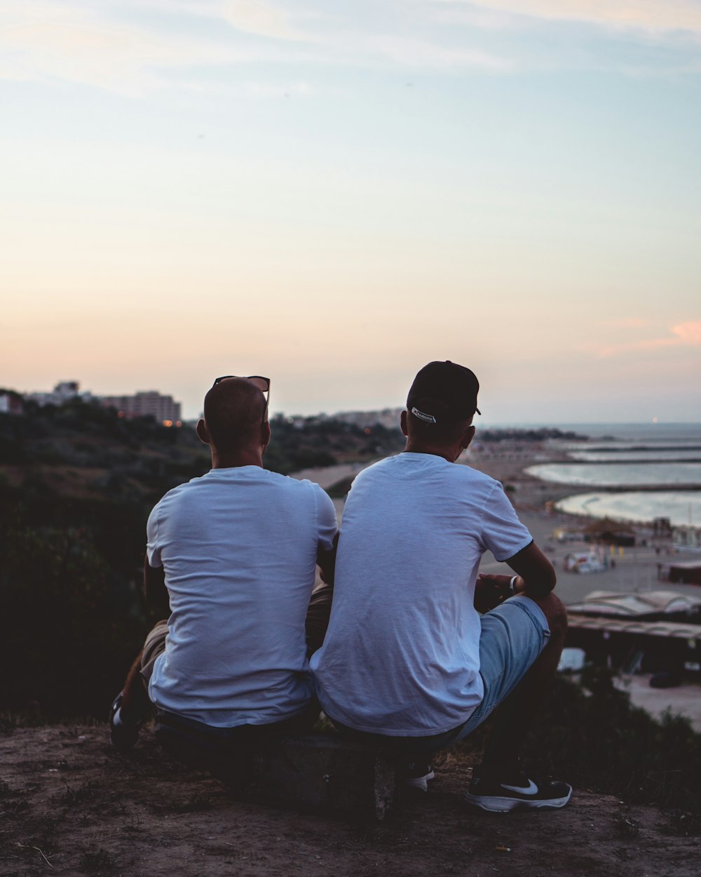 two men sitting at a cliff