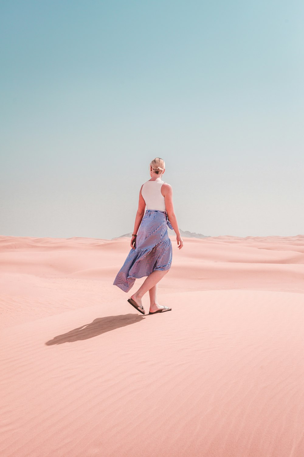 woman wears dress walks on the desert during daytime