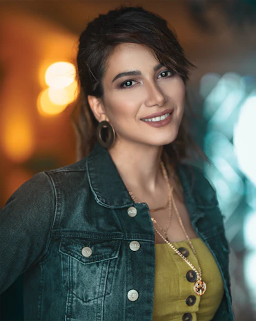 Happy customer wearing delicate earrings, smiling softly in a warm, neutral-toned room.