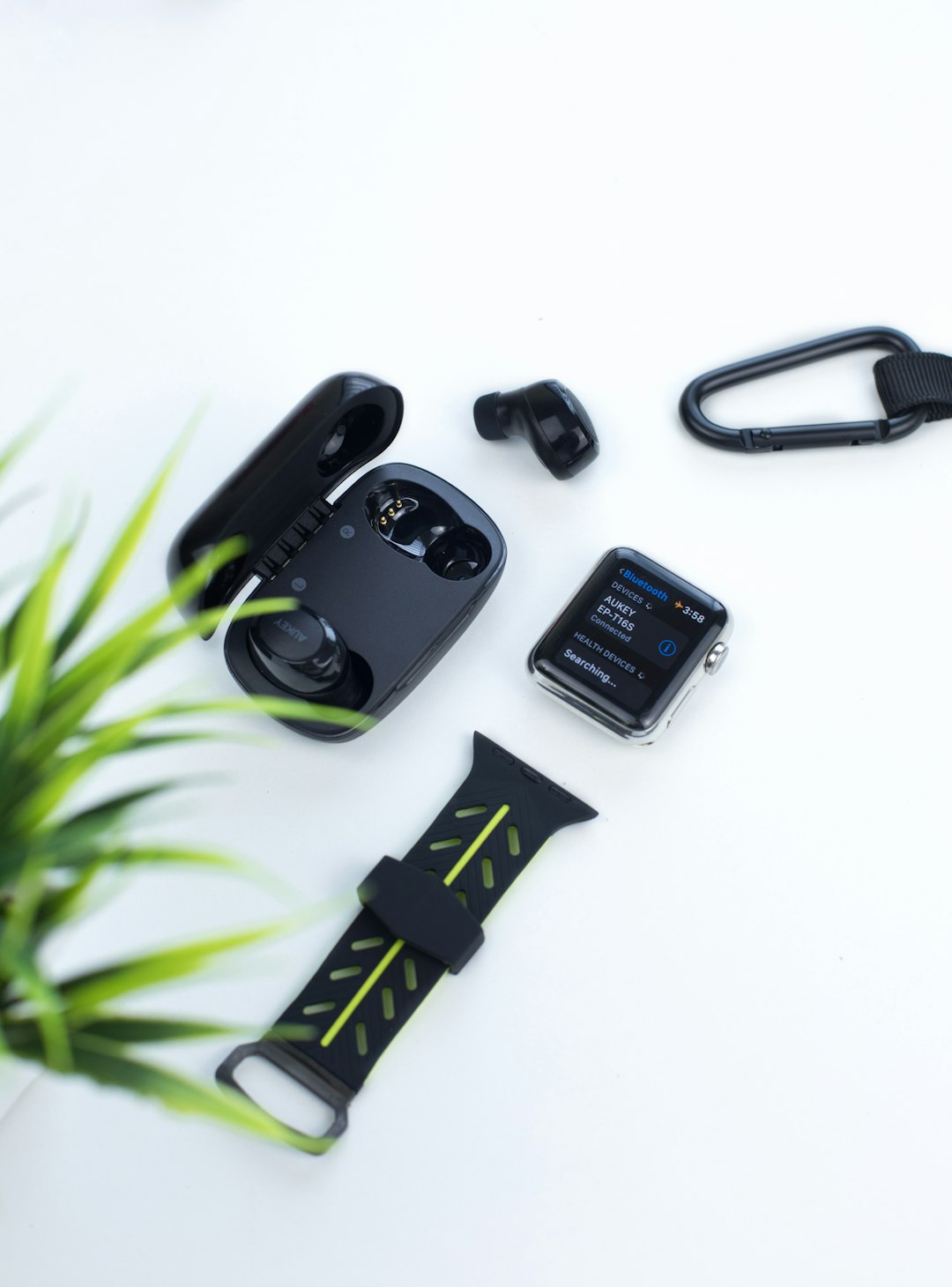 black Apple Watch with black band and black earbuds with charging case
