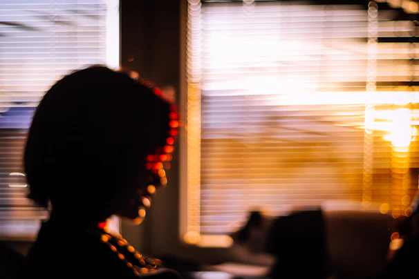 A silhouette of a woman by a window, bathed in warm sunset hues, suggesting intimacy.