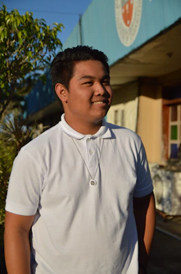 Model wearing a crisp white polo shirt against a sunny outdoor backdrop.