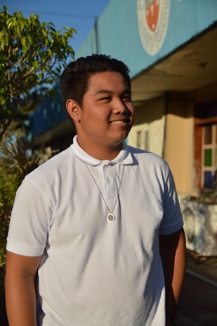 Man wearing a crisp white polo shirt standing outdoors on a sunny day.