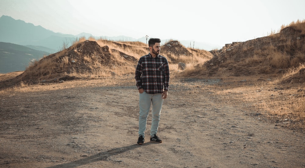 man standing in a field under white clouds during daytime