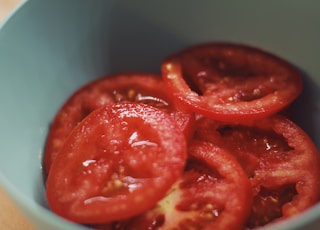 macro photography of sliced red tomatoes in green bowl