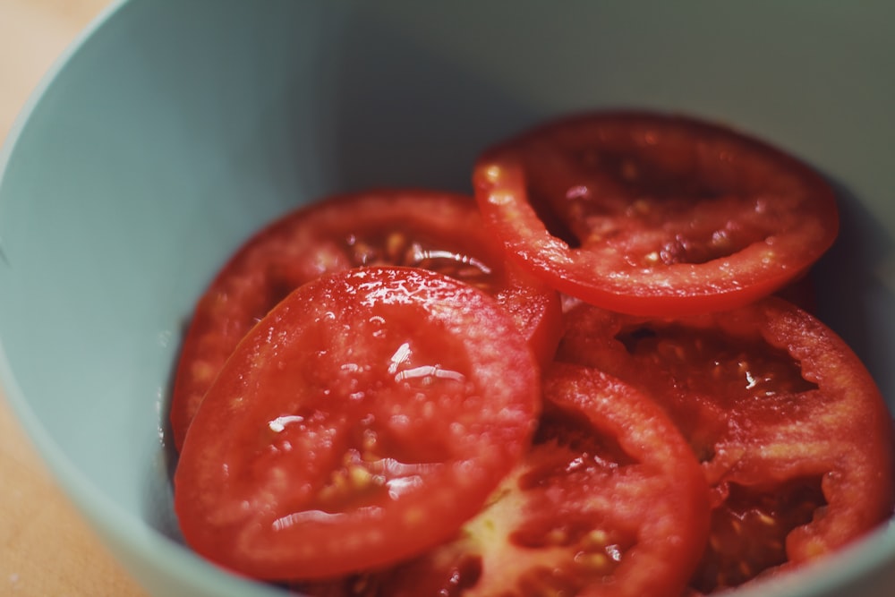 macro photography of sliced red tomatoes in green bowl