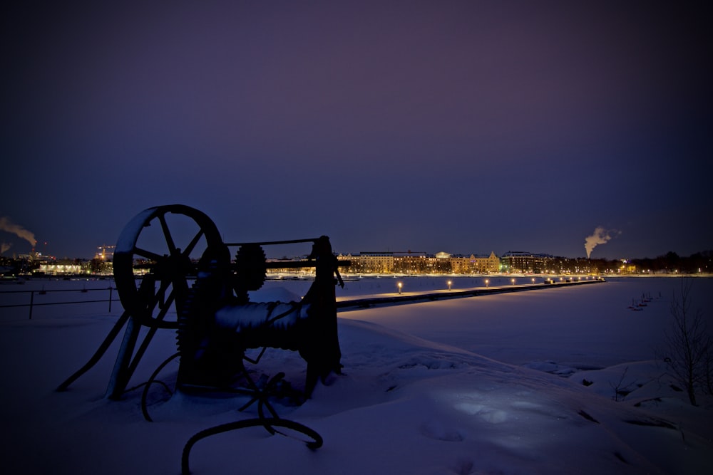 a snow covered field next to a river at night