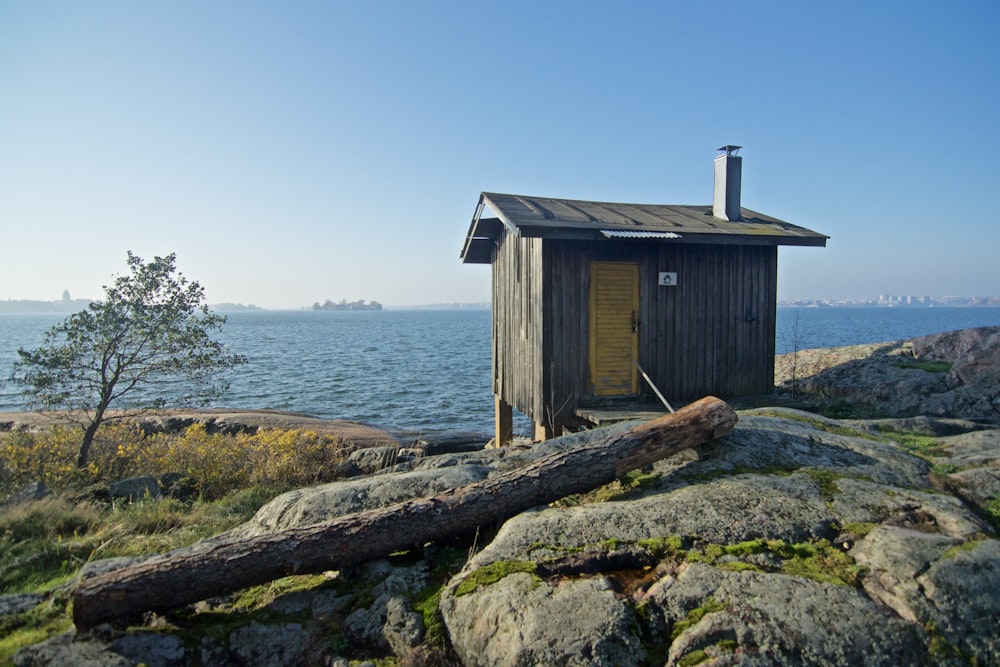 brown wooden shed near body of water under blue sky
