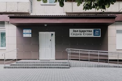 Entrance of a kost building with a welcoming sign in red and yellow tones.