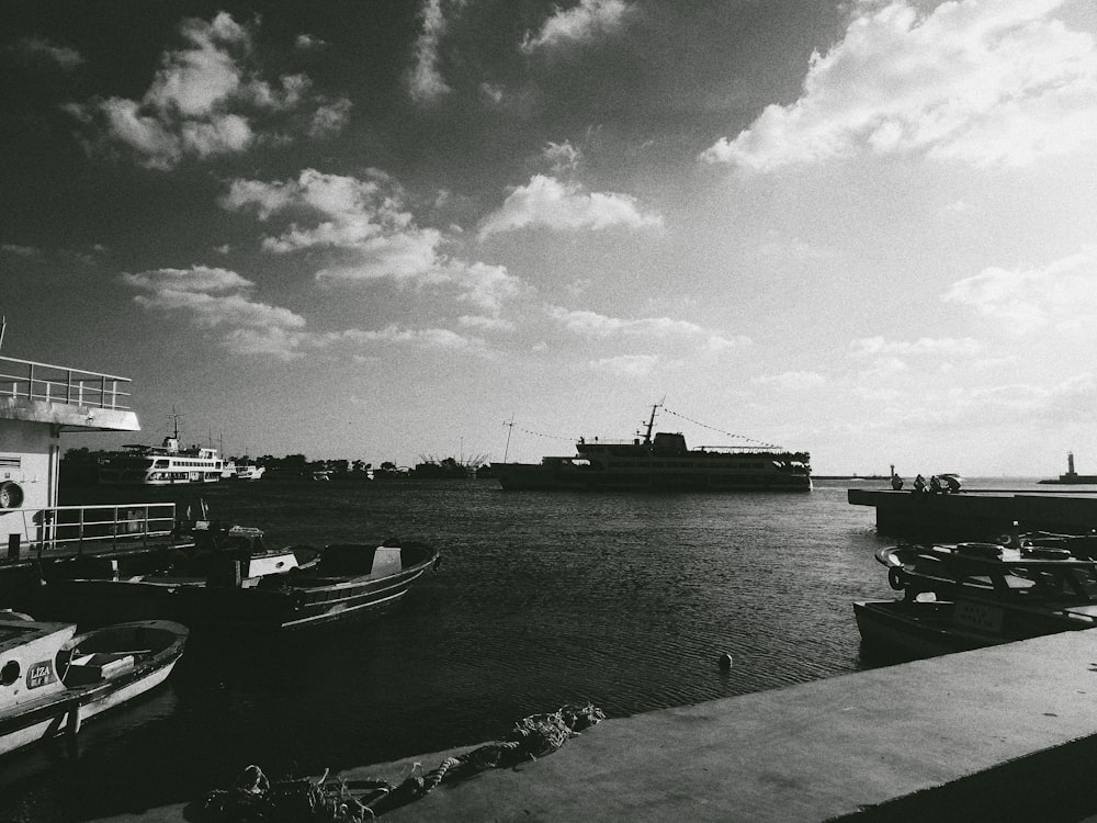 boat on body of water near dock in grayscale photo