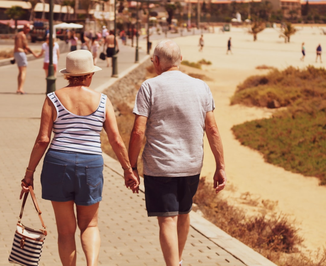 man and woman walking on road while holding hands