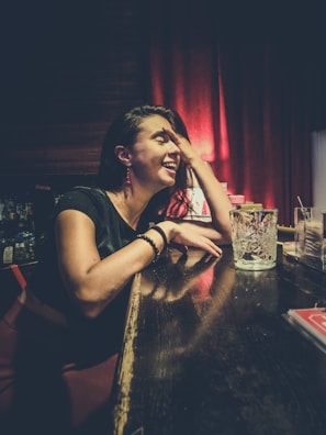 A charming woman laughing softly while seated at a chic lounge bar.