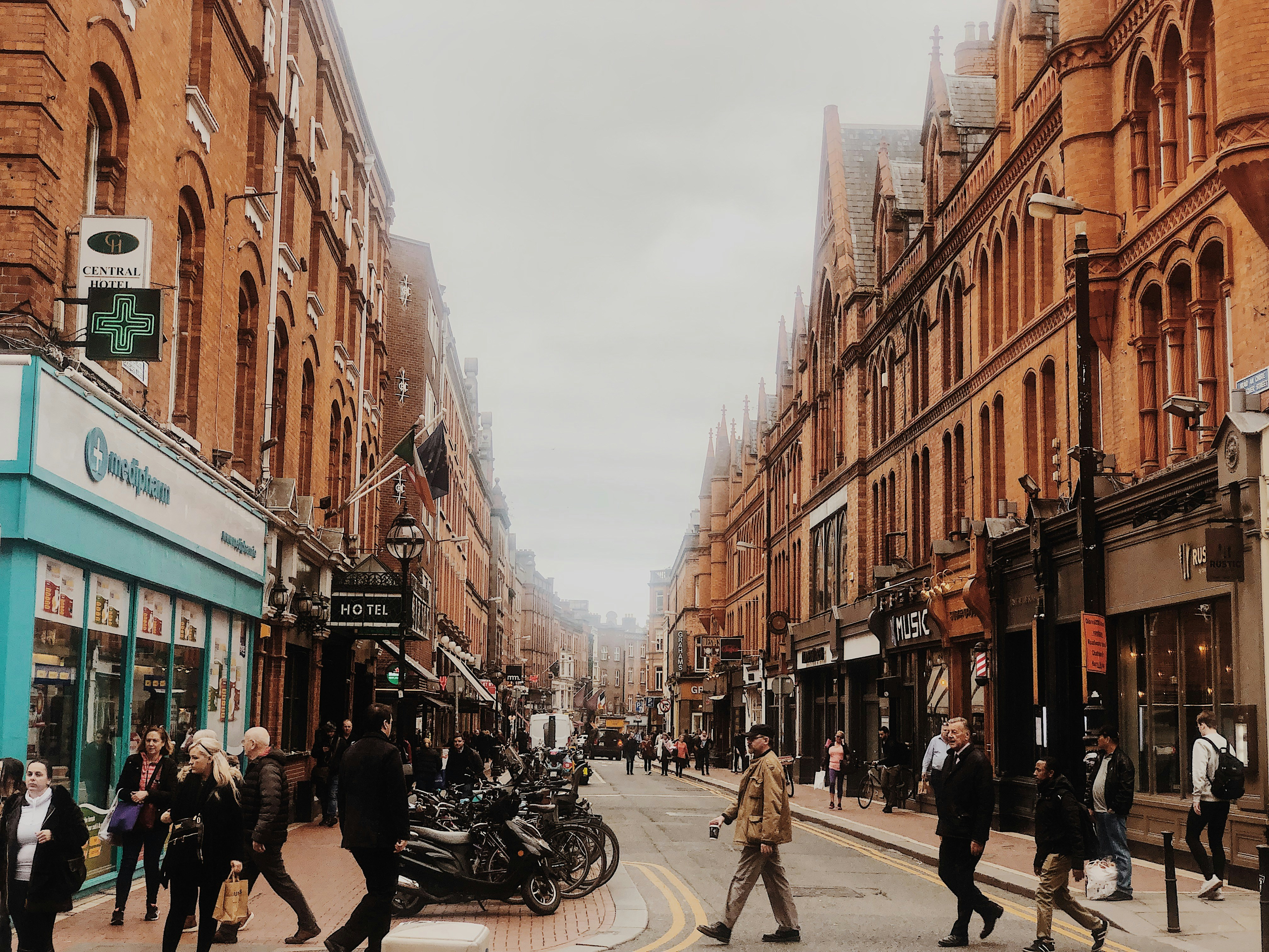 people crossing on road between brown buildings