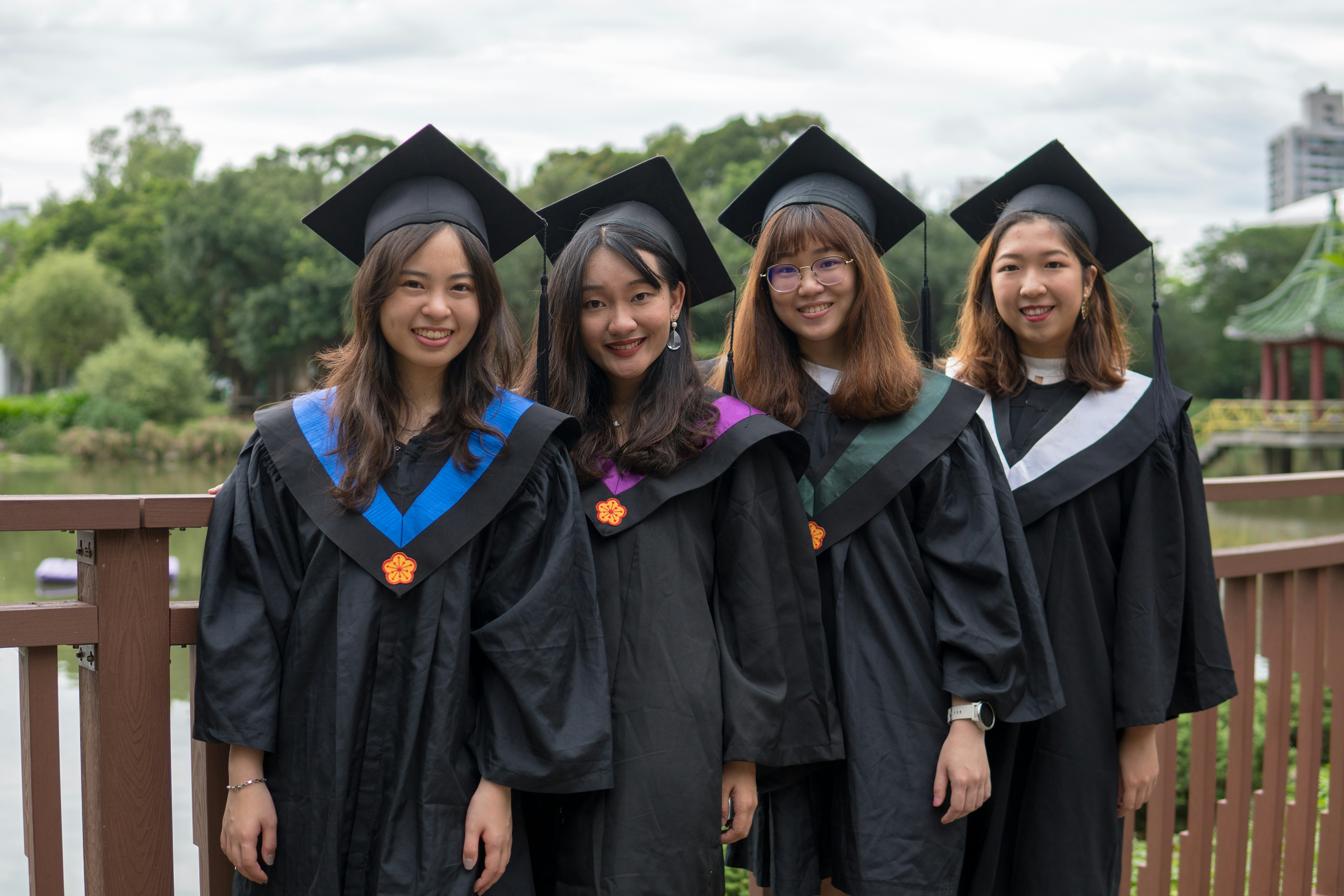 four women wearing black graduation robe and mortar hats