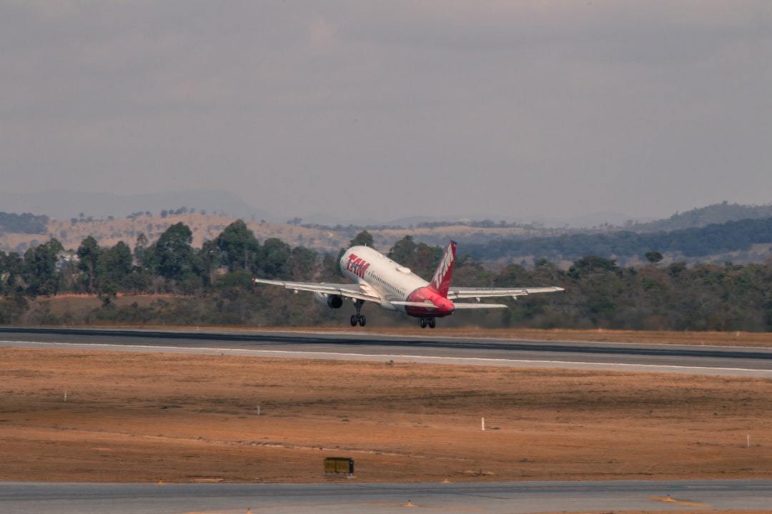 white and red airplane in a runway, Airbus A-319 departing from Confins International Airport
