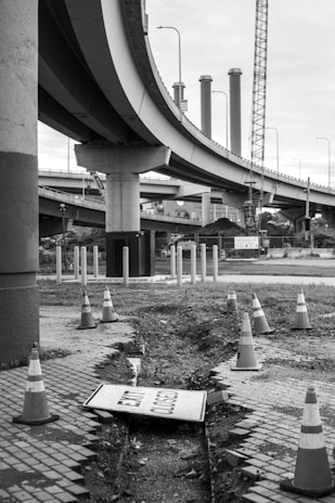 Crash cushions positioned strategically at a roadside construction site, highlighted against deep charcoal black asphalt.