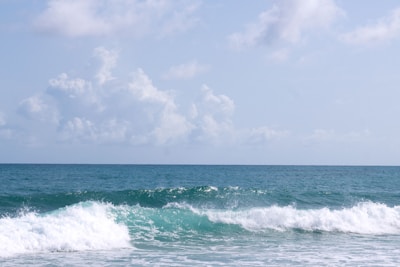 Waves gently crashing on a sandy beach under clear blue skies.