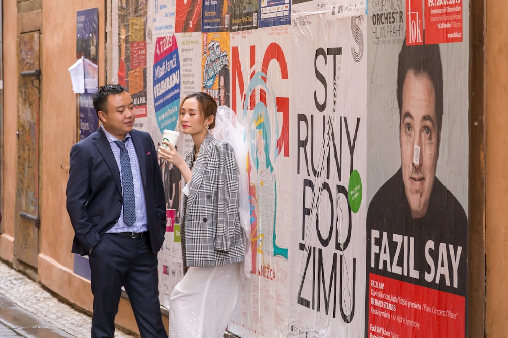 man wearing black formal suit standing and chatting near woman holding cup