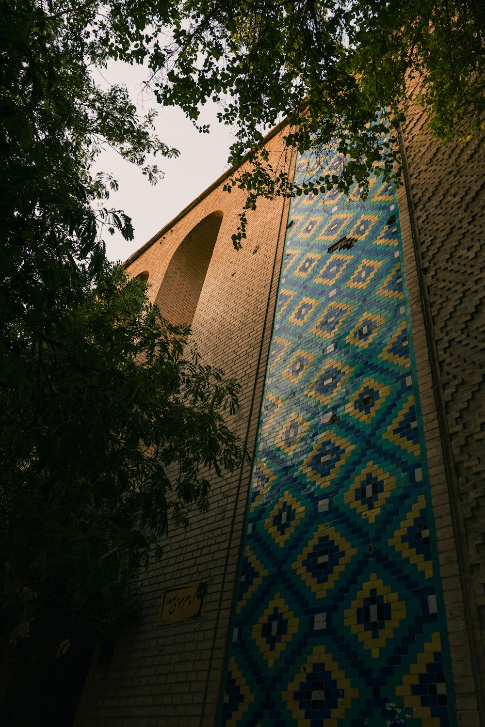 low-angle photography of brown and blue concrete wall near trees