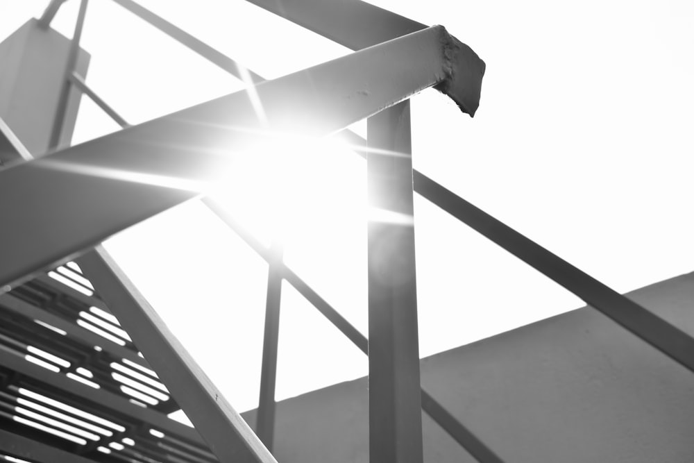 a close up of a metal structure with the sun behind it