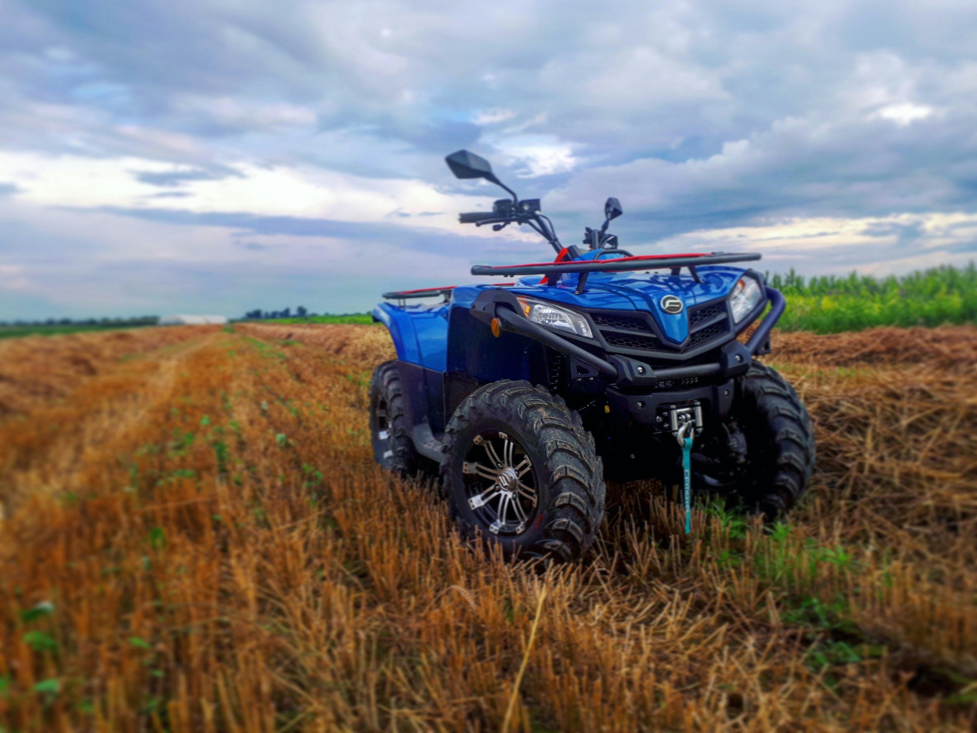 parked blue ATV on dried grass