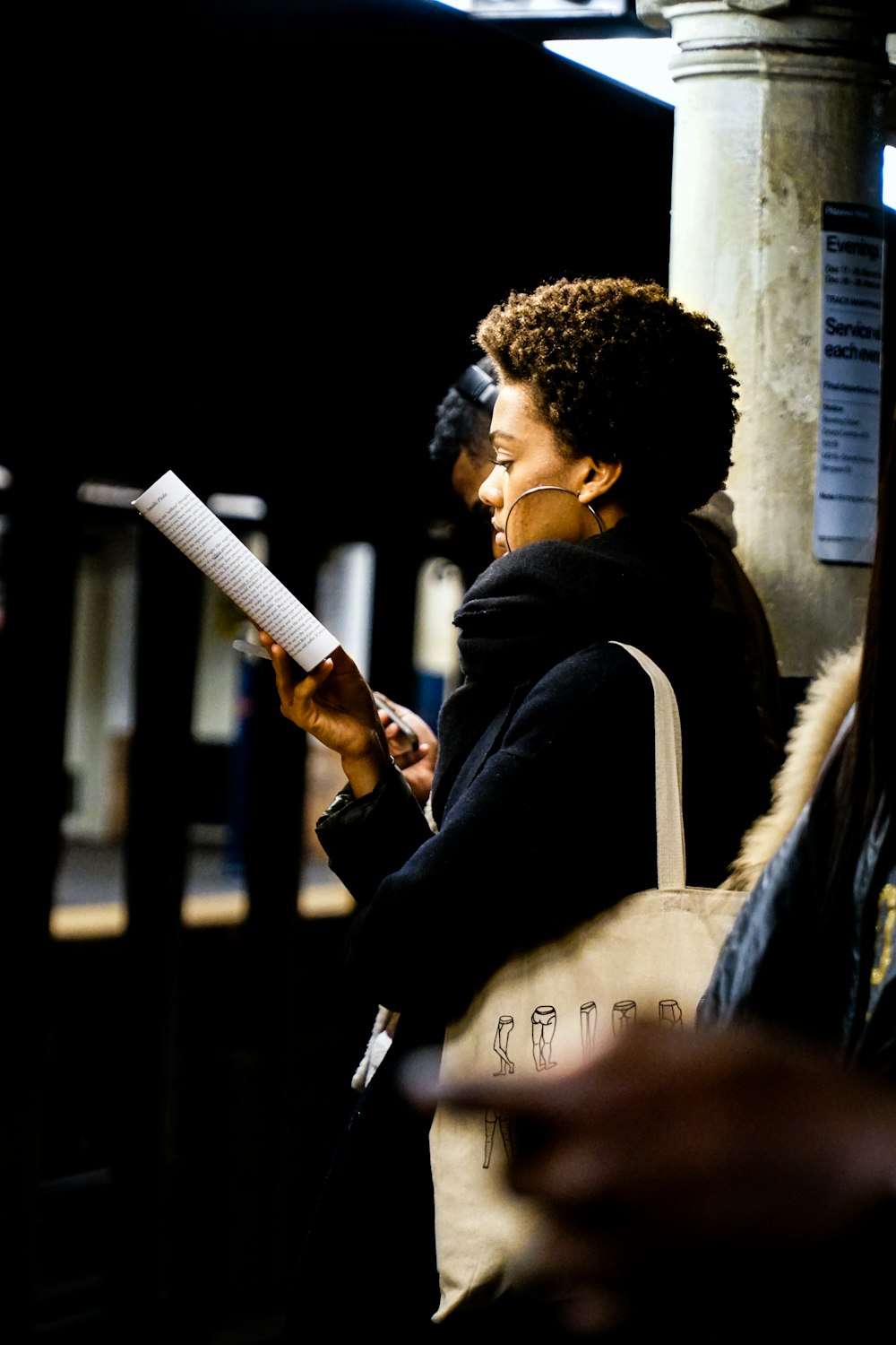 woman reading book while waiting in a train station