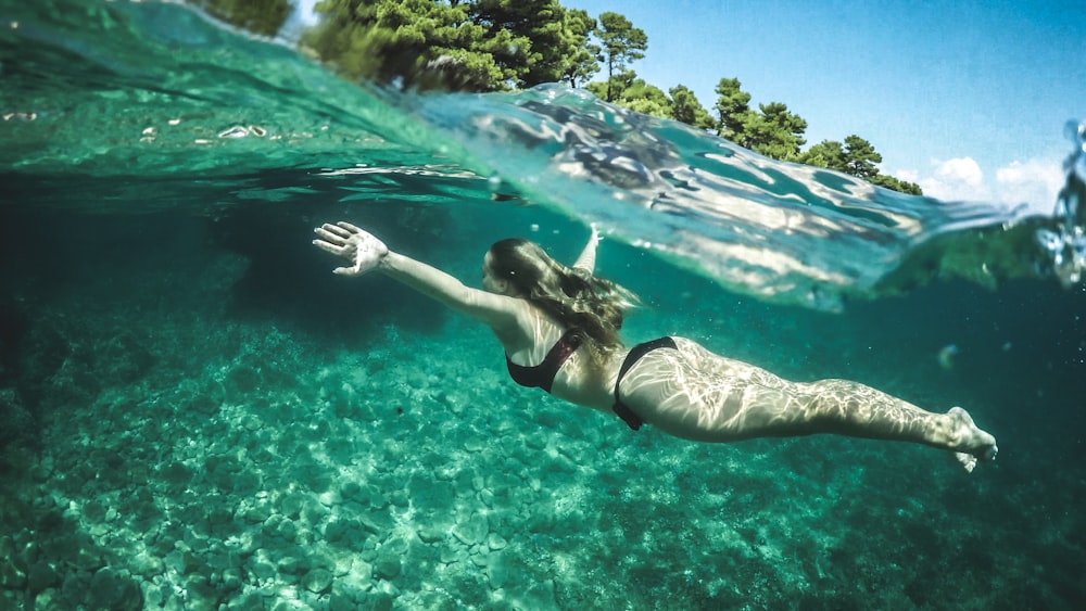 woman in black bikini swimming during daytime