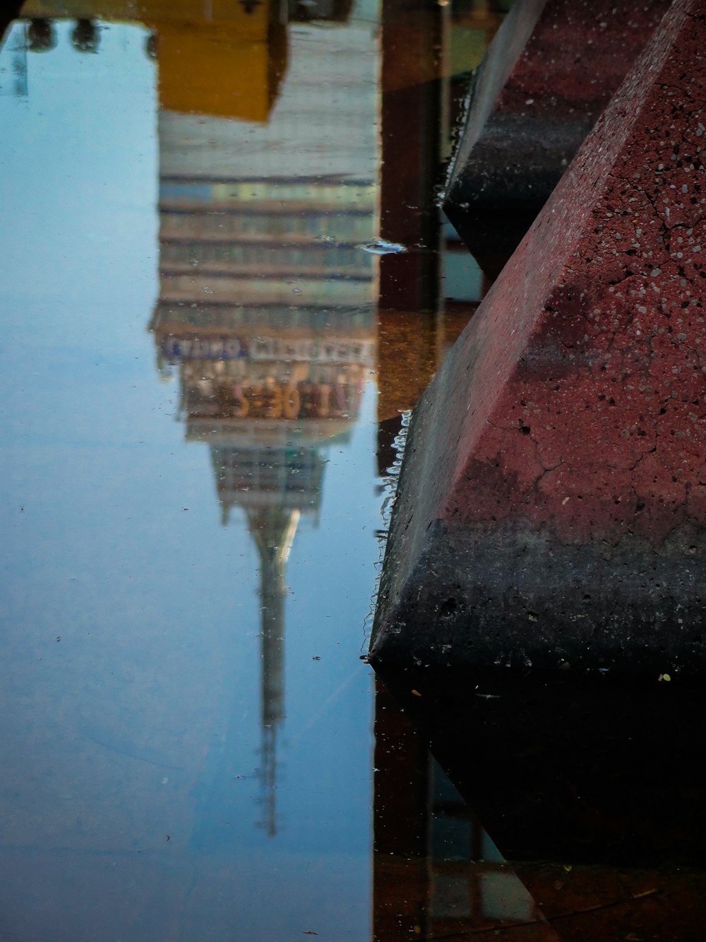 a reflection of a building in a puddle of water