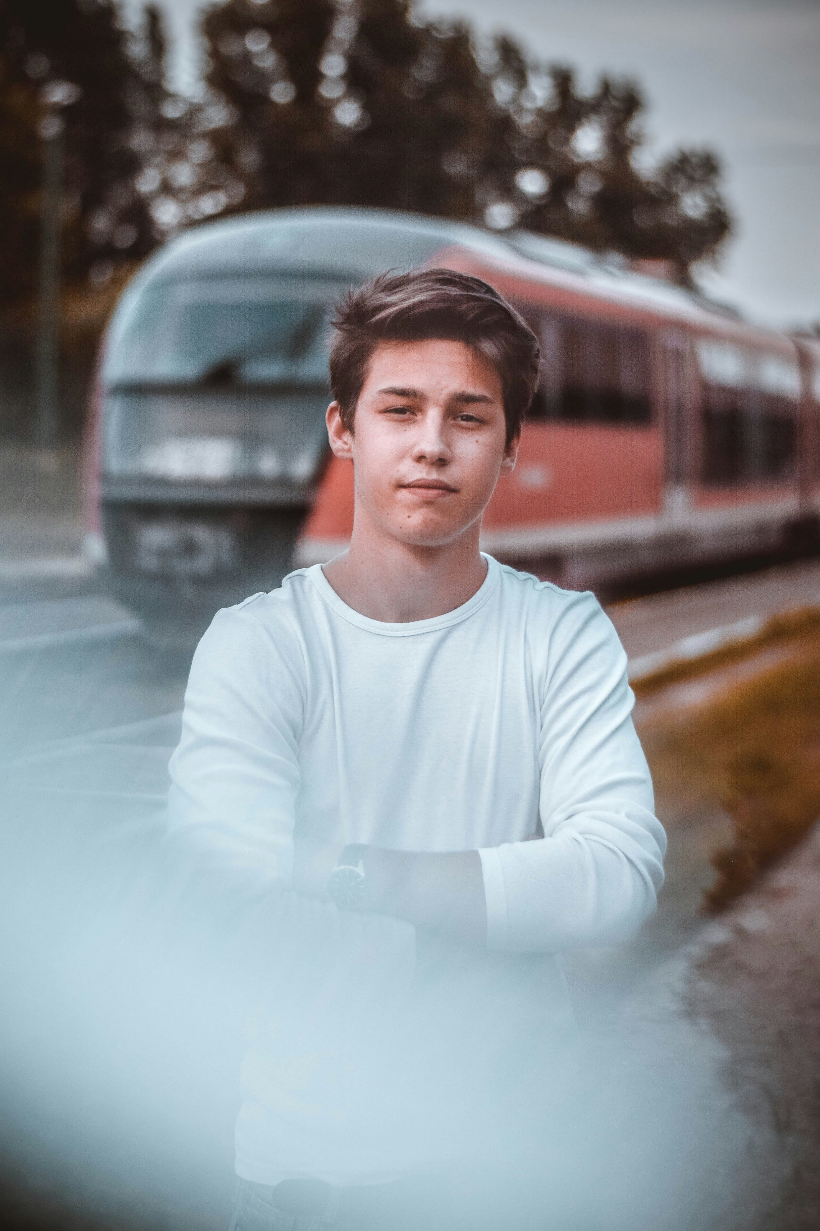 man wearing white crew-neck long-sleeved shirt standing near train
