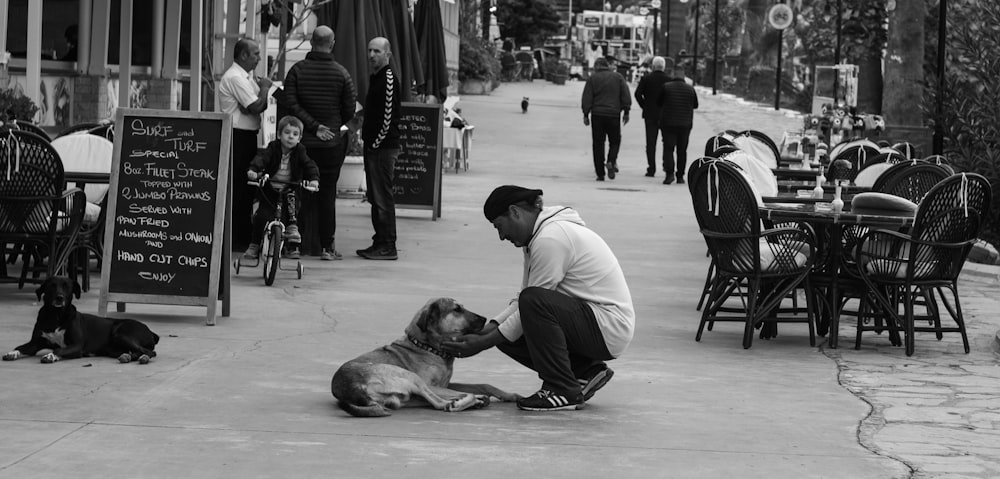 greyscale photography of man sitting beside dog