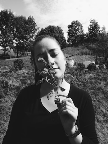 A woman enjoying a peaceful moment outdoors, holding a wellness product with a serene expression.