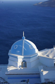 A modern Greek villa overlooking the Aegean Sea under a bright blue sky.