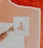 A hand holds up an artwork in front of a textured wall. The artwork depicts a vintage perfume bottle labeled with the word 'positivity' and small floral details. The wall has a peach and white abstract mural design.