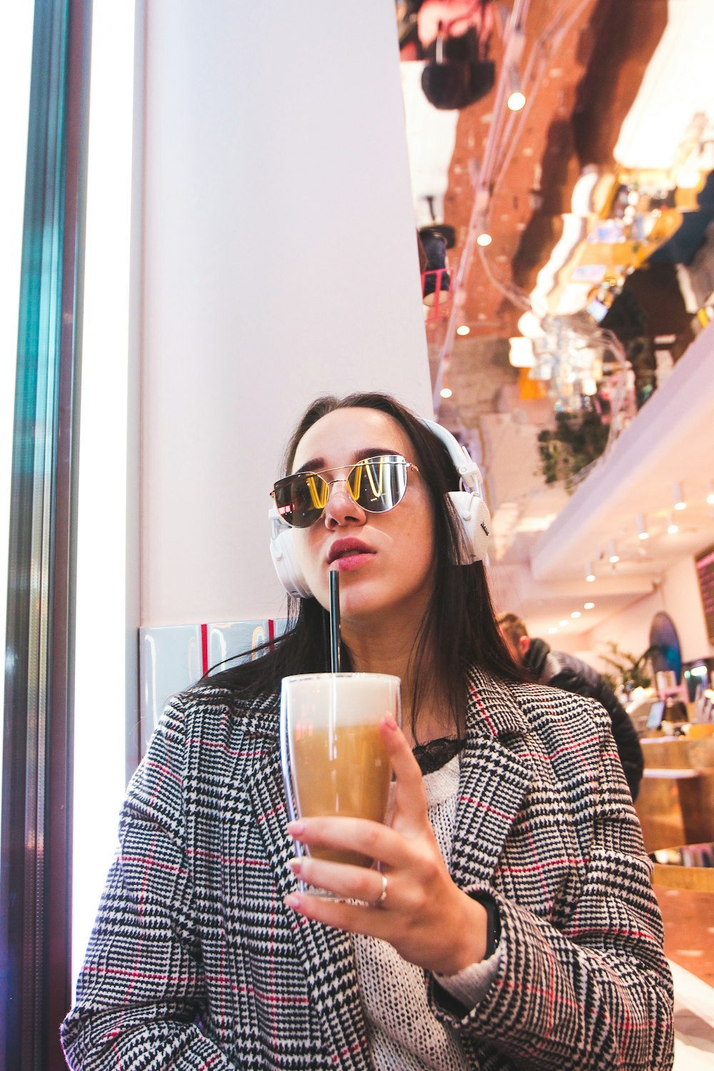 woman with headphones hold cold beverage inside mall