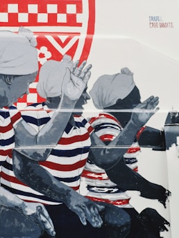 A mural depicts three figures wearing headscarves and striped shirts in red, white, and blue, gesturing energetically. There is a vibrant red and white pattern in the background.