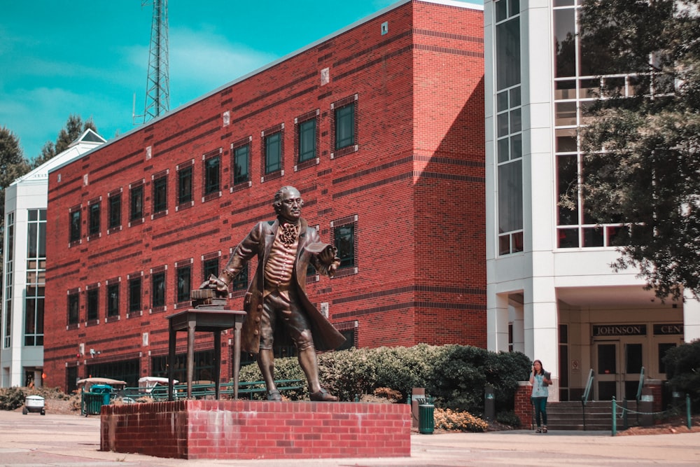 man statue near red building
