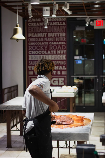 A chocolatier carefully handcrafting delicate chocolate pieces in a cozy workshop setting