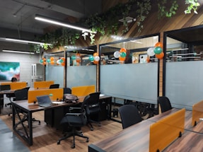 A cheerful workspace with colorful balloons and fresh flowers arranged on a wooden table.