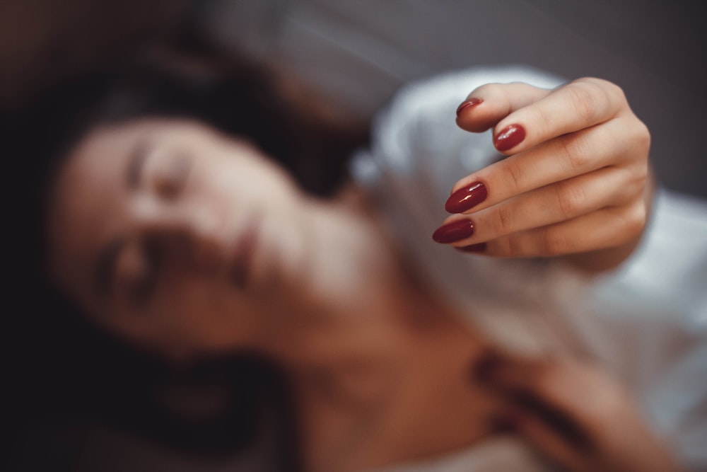 a close up of a woman with a red manicure on her nails