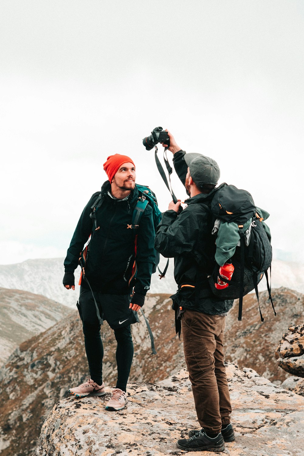 two men standing beside cliff during day