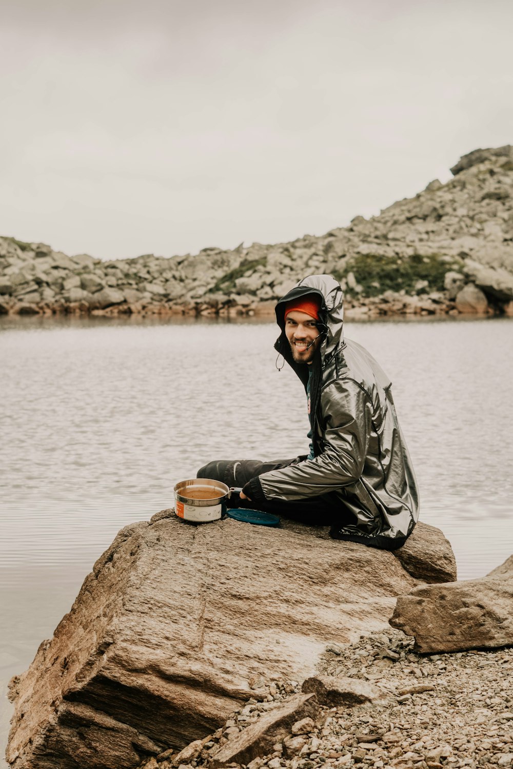 man sitting on rack near body of water during daytime